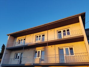 Een meerlaags gebouw met balkons, ramen en een heldere lucht.