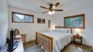 A bedroom with a wooden bed, a ceiling fan, a television, and two windows. - Cozy Worley Cabin w/ Lake Access + Gas Grill! (Worley)