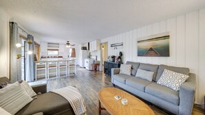 A spacious living area with a grey sofa, a wooden coffee table, and a kitchen in the background. - Cozy Worley Cabin w/ Lake Access + Gas Grill! (Worley)