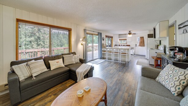 A spacious living area with a sofa, a coffee table, and a kitchen in the background. - Cozy Worley Cabin w/ Lake Access + Gas Grill! (Worley)