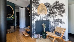 A modern living room with a large wall mural, a hanging rattan light fixture, and a wooden bench. - Bruges, Near Bordeaux: Charming, Air-Conditioned House with a Pool and Garden (Bruges proche Bordeaux)