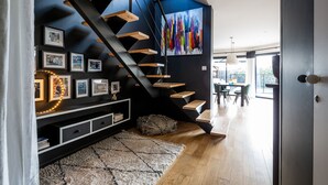 A modern staircase with wooden steps and black railings, leading to a dining area with a view of the outdoors. - Bruges, Near Bordeaux: Charming, Air-Conditioned House with a Pool and Garden (Bruges proche Bordeaux)