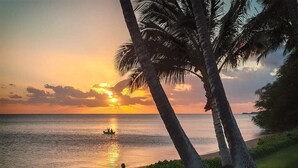 A sunset view with palm trees and a calm sea. - Island Inspired w/Loft, Large Lanai, Kitchen #334 (KAUNAKAKAI)