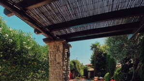 A pool area with stone pillars, lounge chairs, and a pergola.
