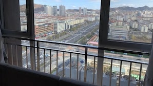 A cityscape through a window with a view of buildings, roads, and a distant mountain range. - Ibis Hotel (Weihai Dongfang Xintiandi) (Weihai)