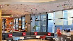 A modern interior with a curved sofa, bookshelves, and a desk area. - Ibis Hotel (Weihai Dongfang Xintiandi) (Weihai)