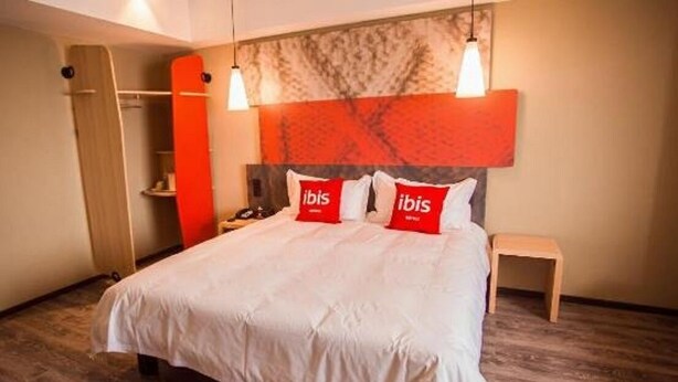 A hotel room with a large bed, two bedside tables, a wardrobe, and a headboard with a red accent. - Ibis Hotel (Weihai Dongfang Xintiandi) (Weihai)