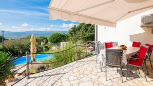 Une terrasse avec un sol en pierre, des sièges d’extérieur, une piscine et une vue sur le paysage.