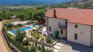 Un bâtiment à deux étages, doté d’un toit recouvert de tuiles rouges, d’une piscine et d’un terrain de jeux.