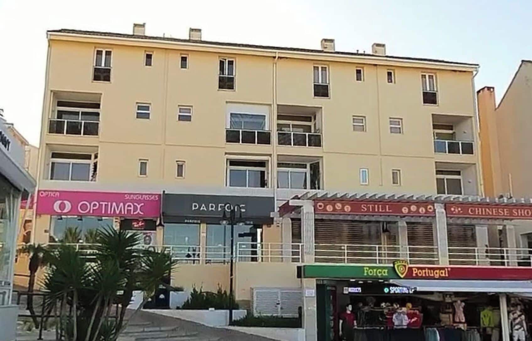 Um edifício de vários andares com diversas lojas, incluindo Optima, Parfure, Still e Loja Chinesa.