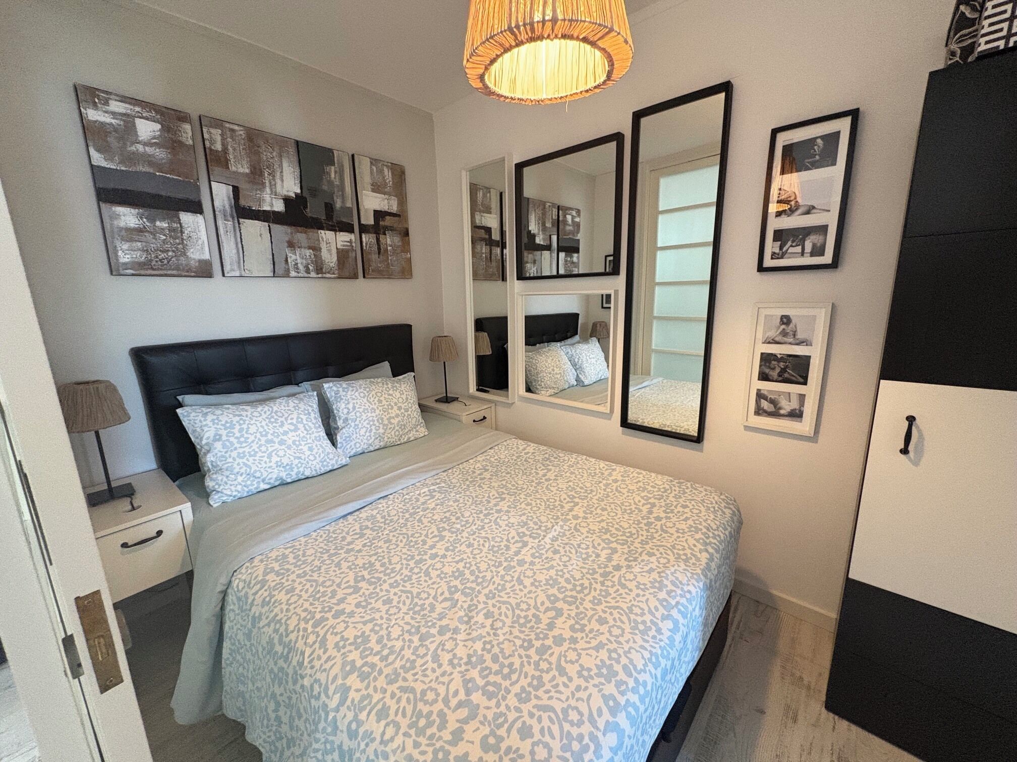Un dormitorio con cama, mesitas de noche, armario y decoración en la pared.