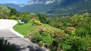 Un jardin agrémenté d’une allée sinueuse, d’une végétation luxuriante et dominé par une chaîne de montagnes.