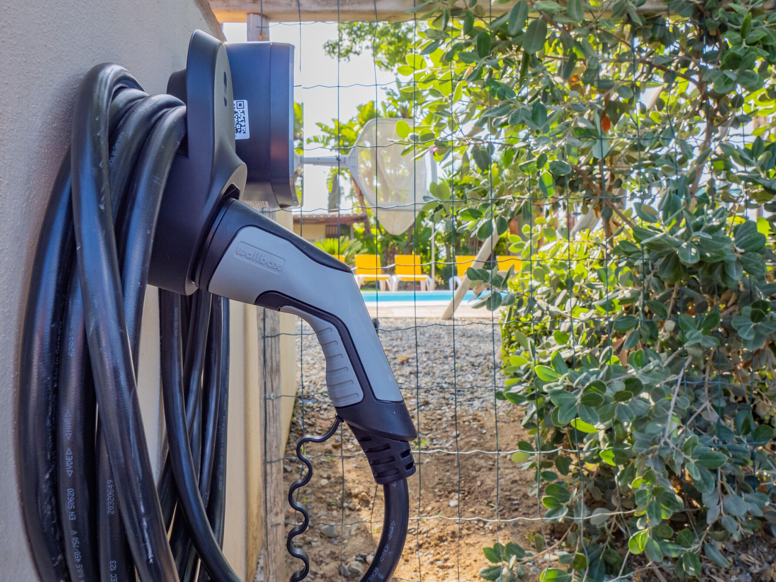 En vægmonteret elbil-ladestation med tilsluttet ladekabel.