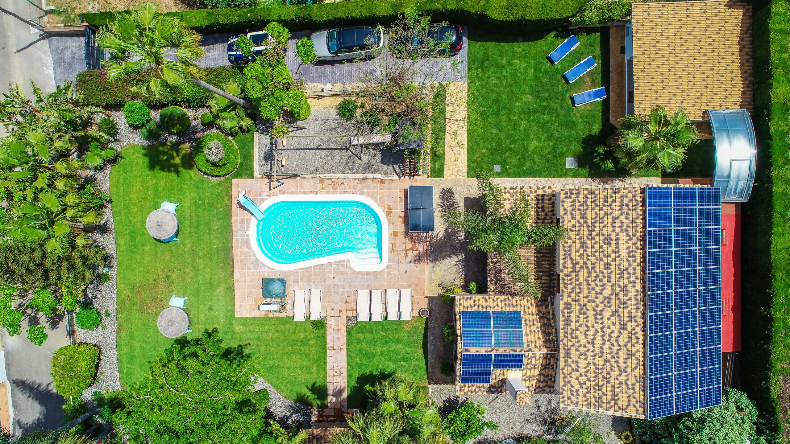 Ovenfra ses en bolig med swimmingpool, liggestole og solpaneler.