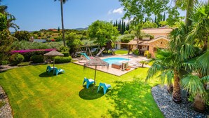 A well-maintained backyard with a swimming pool, a wooden play structure, and a patio area with outdoor furniture.