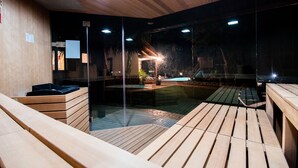 A modern indoor pool area with wooden decking and glass walls.