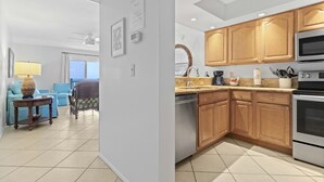 A modern kitchen with wooden cabinets, stainless steel appliances, and a view of the ocean. - Gulfside Comfort – Beach Castle #4 by RVA (Longboat Key)