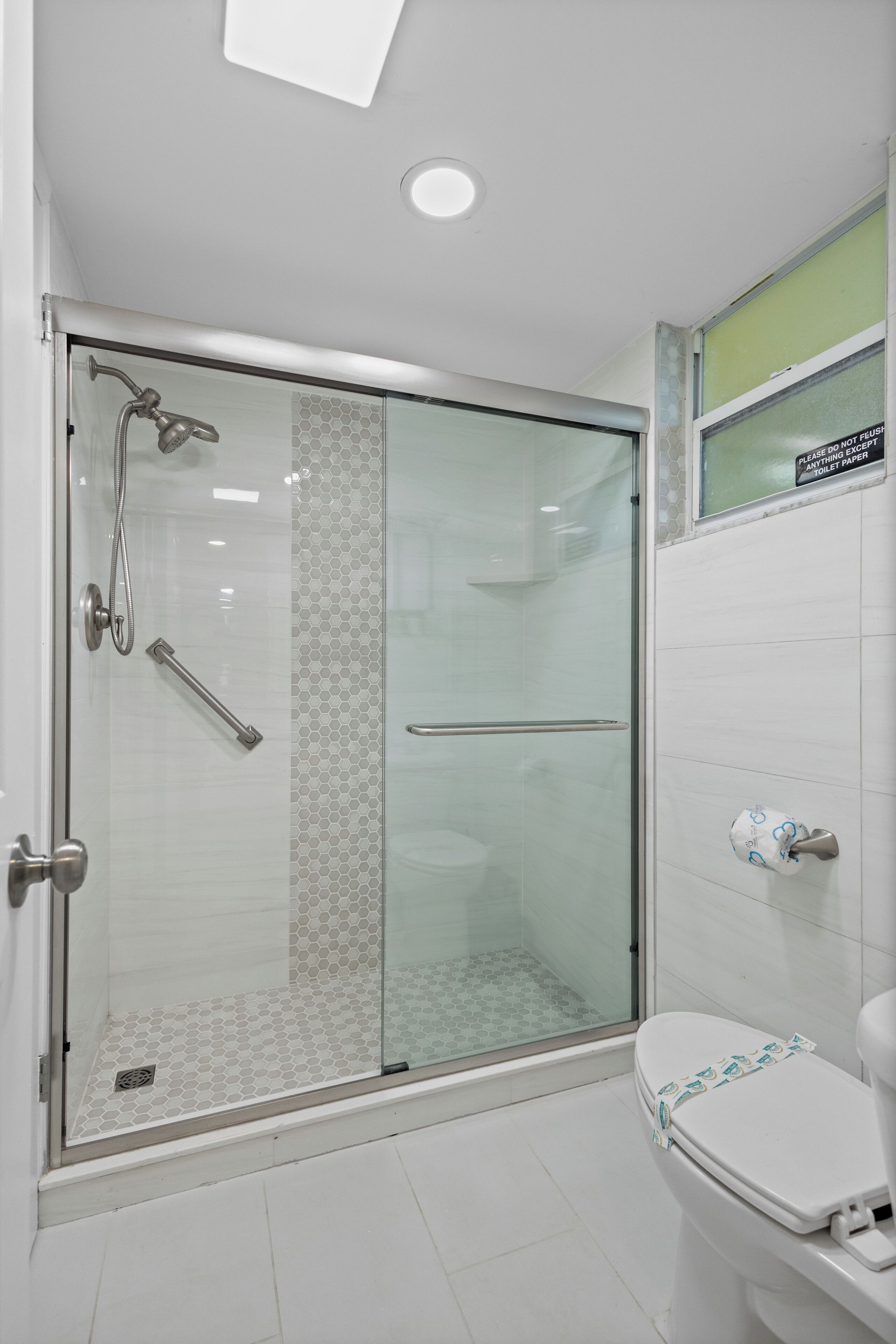 A modern bathroom with a glass-enclosed shower, a toilet, and a sink.