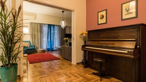 Ein Wohnzimmer mit einem Klavier, einer Topfpflanze, einem roten Teppich und einer Kronleuchter.