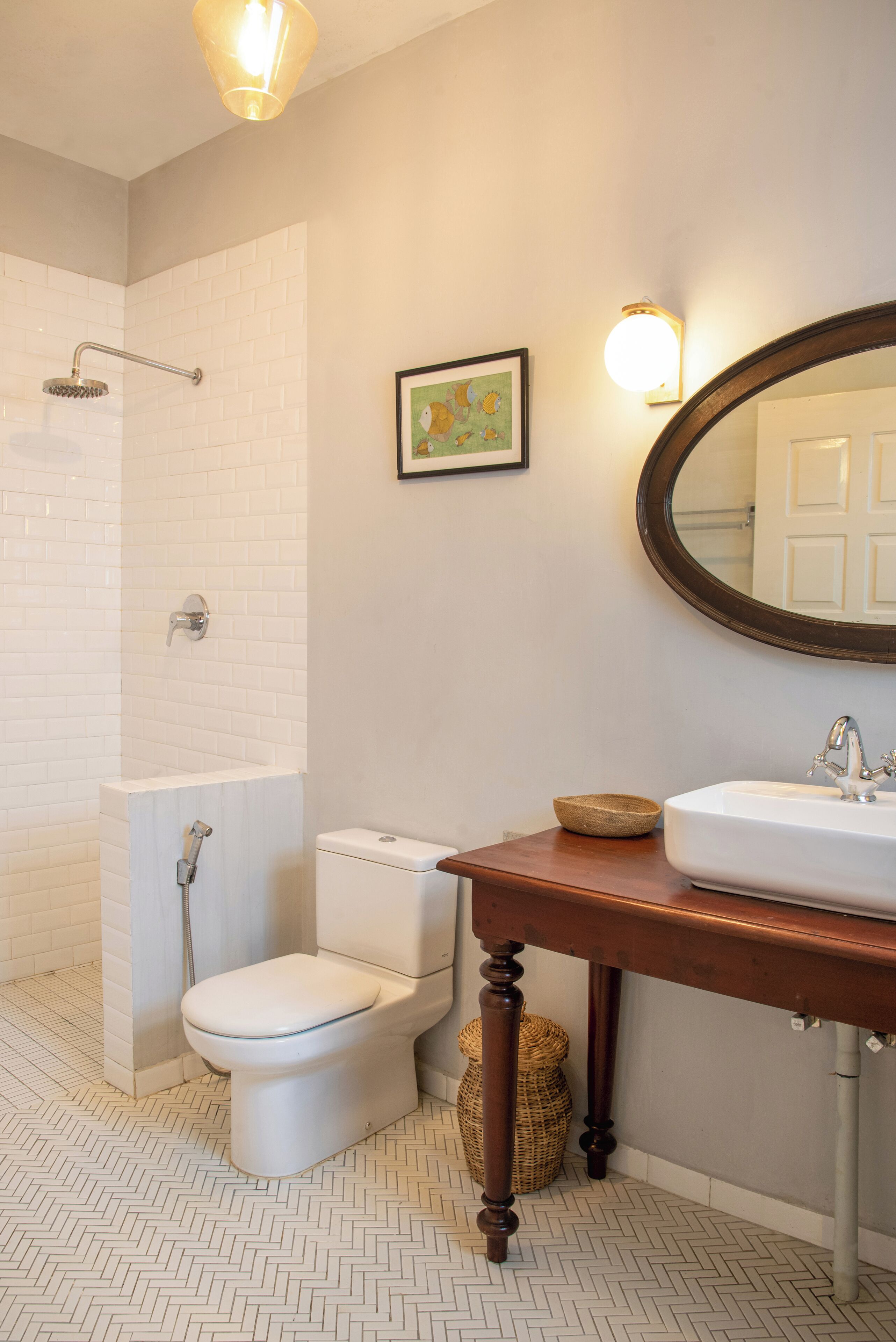 A bathroom with a white tiled shower, a white toilet, a wooden vanity with a sink, and a mirror.