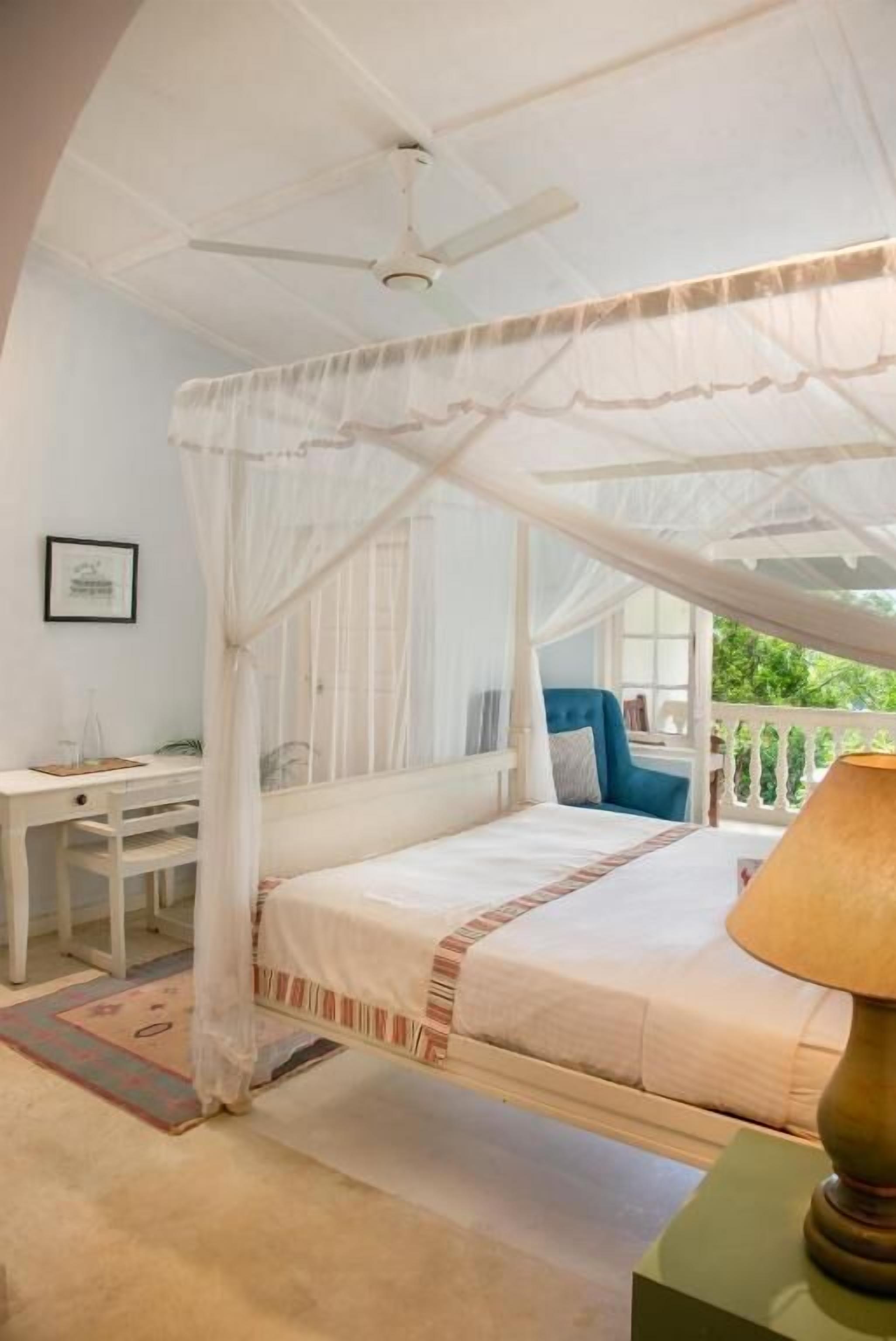 A bedroom with a canopy bed, a desk, and a chair.