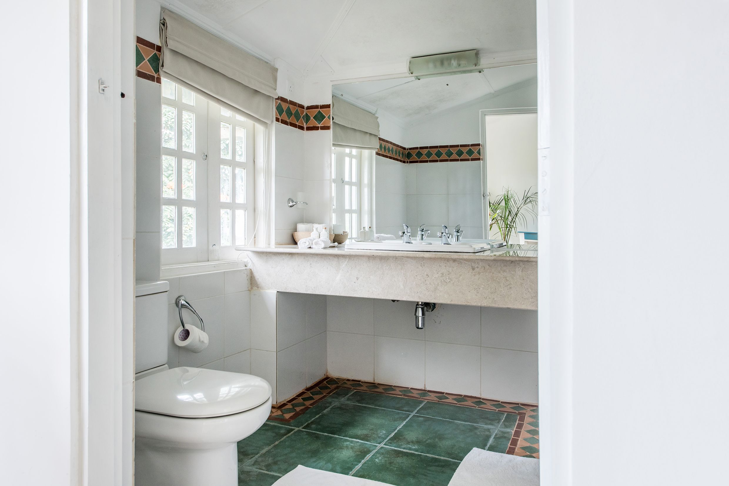 A bathroom with a toilet, sink, and mirror.