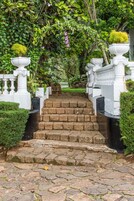 Una escalera de piedra conduce a una estructura blanca rodeada de abundante vegetación.