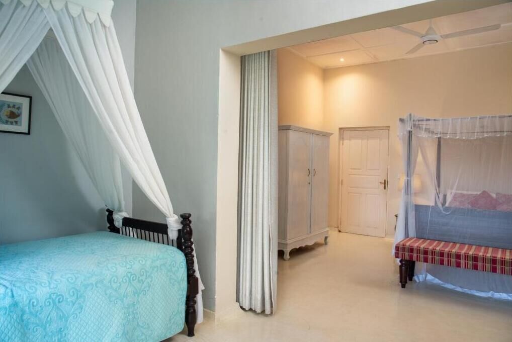 Quarto com cama, guarda-roupa, um banquinho e uma porta.