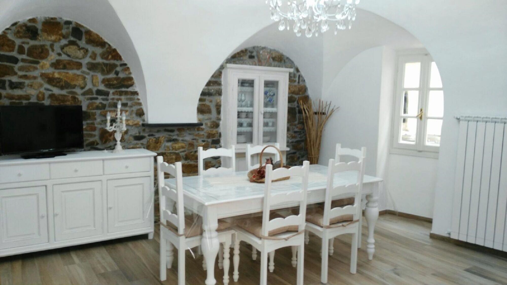 A dining area with a stone wall, white cabinets, and a chandelier.