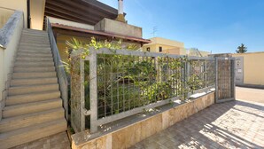 A residential building with a staircase, a fenced garden area, and a tiled patio. - Appartamento Solaris by BarbarHouse (Nardò)