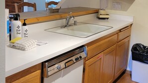 A kitchen with wooden cabinets, a white countertop, a dishwasher, and a toaster.