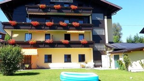A multi-story building with a sign reading "APPARTMENT" and "Ströbler Frisierstube". - Apartment garden view - Apartment house Roland (Strobl)