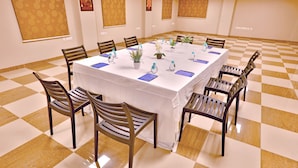 Una sala de conferencias con una mesa grande, sillas, plantas en macetas y botellas de agua.