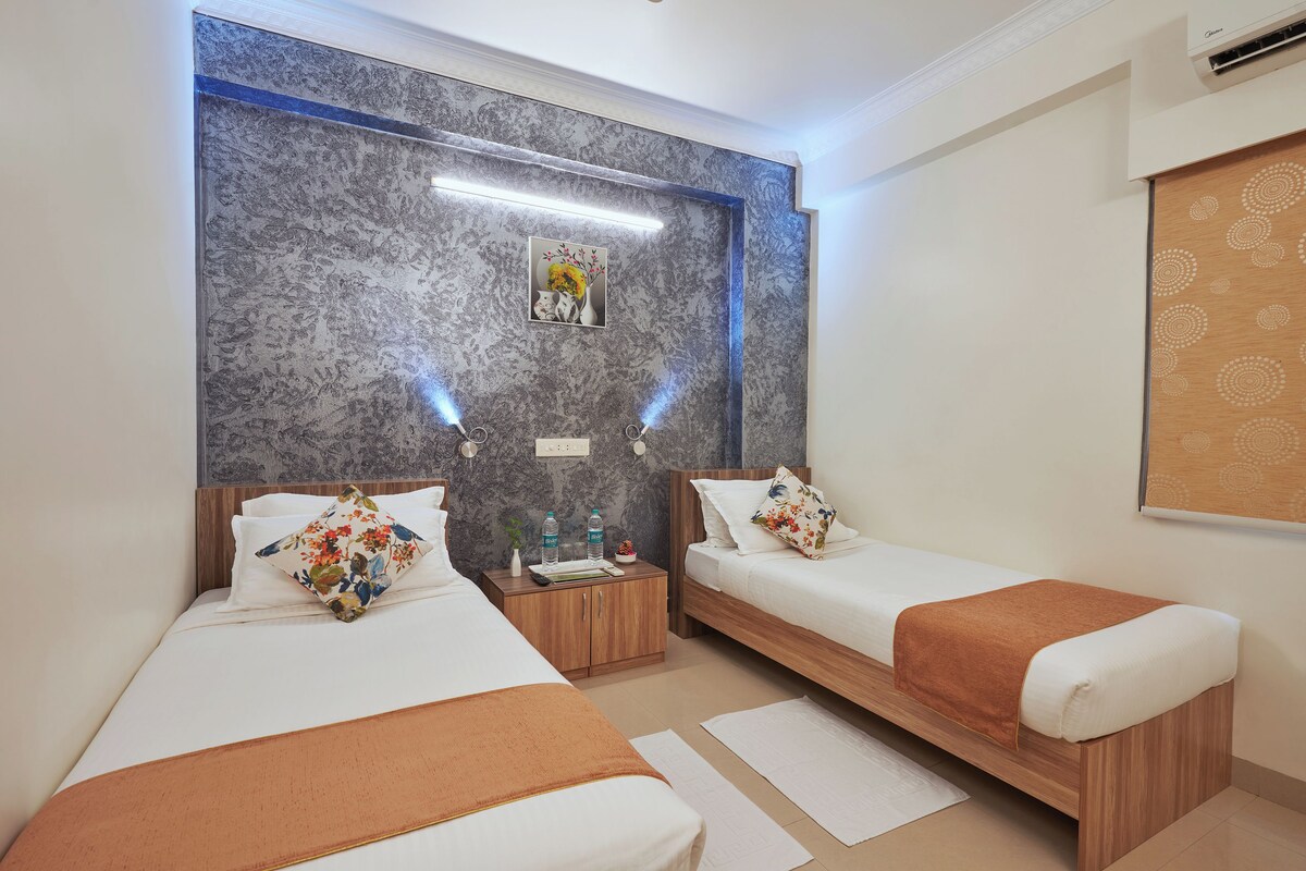 Une chambre d’hôtel avec deux lits, un mur en marbre, une petite table de chevet et un climatiseur fixé au mur.