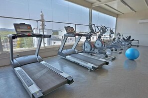 A gym with treadmills, elliptical machines, and a blue exercise ball. - Downtown Business Hotel (Chengalpattu)
