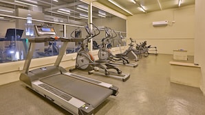 Un gimnasio con cintas de correr, bicicletas estáticas y máquinas elípticas.