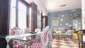 Un coin repas avec une table en verre, des chaises aux motifs rouges et blancs, et un sol à carreaux.