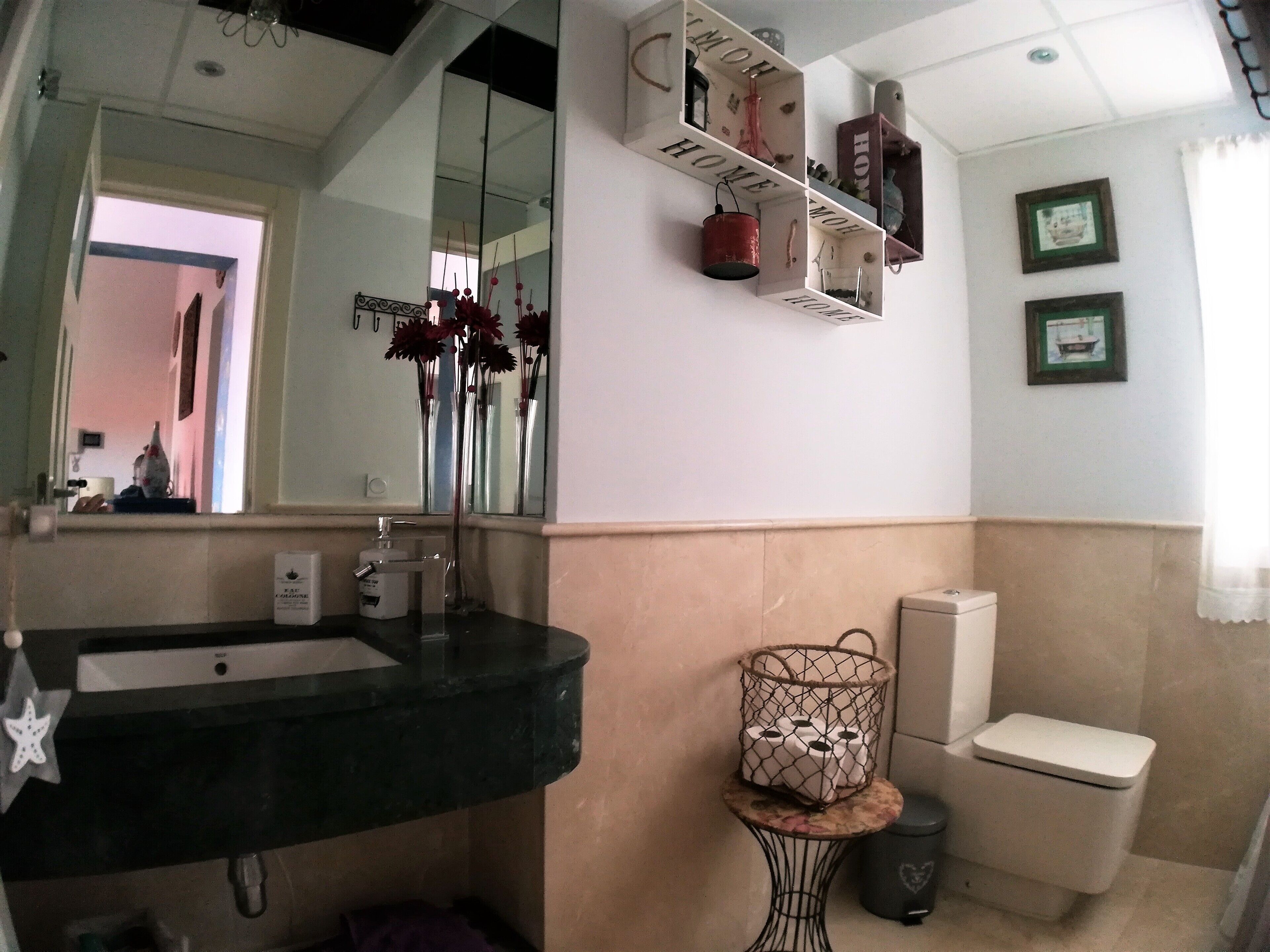 A bathroom with a sink, mirror, toilet, and a small table with a basket.