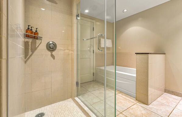 A modern bathroom with a glass-enclosed shower, a white bathtub, and a tiled floor.