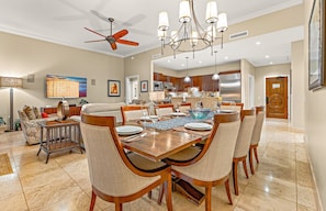 A spacious dining area with a large wooden table, multiple chairs, and a ceiling fan.