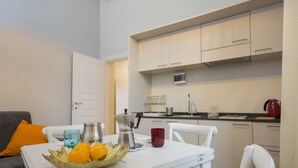 A compact kitchen with white cabinets, a coffee machine, and a kettle on the countertop.