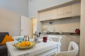 A compact kitchen with white cabinets, a coffee machine, and a kettle on the countertop.