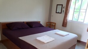 A single bed with a wooden headboard, a purple bedspread, and two white towels on the bed. - Dome Resort (Sena)