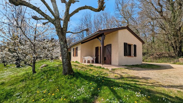 A small, single-story building with a porch, a table, and chairs. - Little House with beautiful view in unique Holiday Resort **** in Dordogne-Lot (Gavaudun)