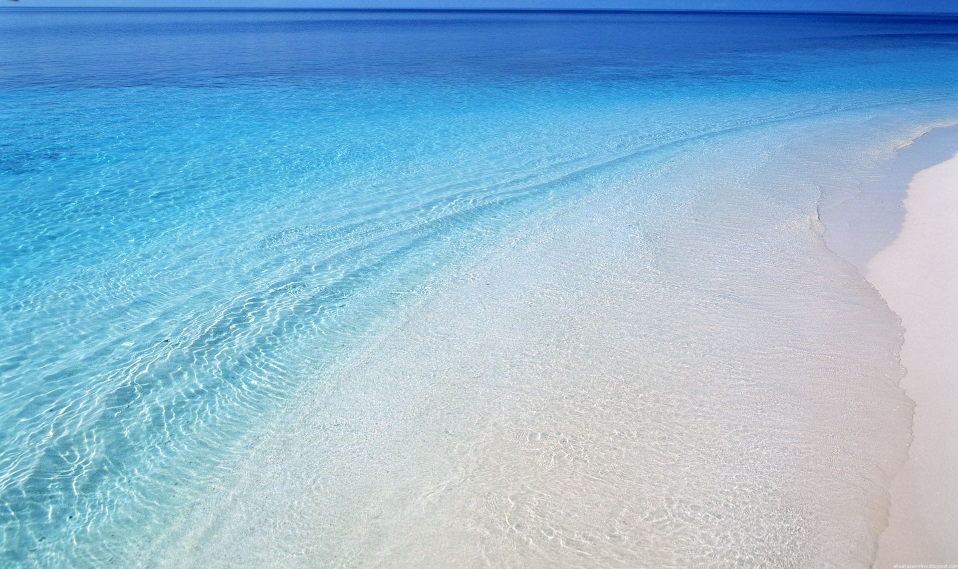 Een strand met helder turquoise water en wit zand.