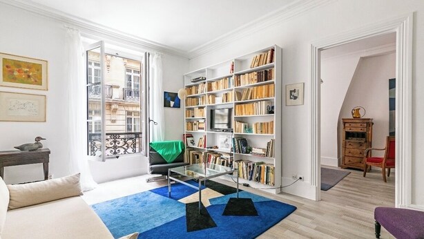 A spacious living room with a large bookshelf, a glass coffee table, and a view of the city through a balcony. - 4 ROOMS COZY, FUNCTIONAL, 4/5 pers NEAR TOUR EIFFEL St GERMAIN ... (Paris)