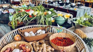 Een buitenterras met bamboemeubilair en een verscheidenheid aan verse ingrediënten op een tafel.