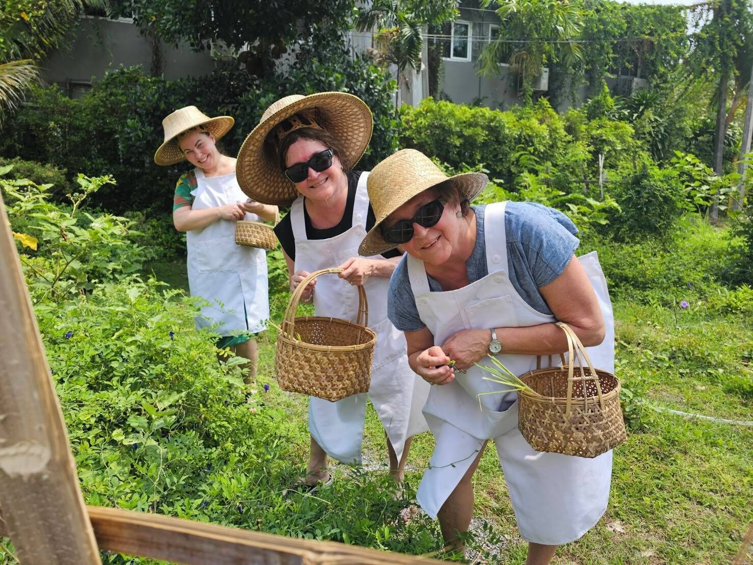 Três pessoas num jardim, cada uma segurando uma cesta de palha.