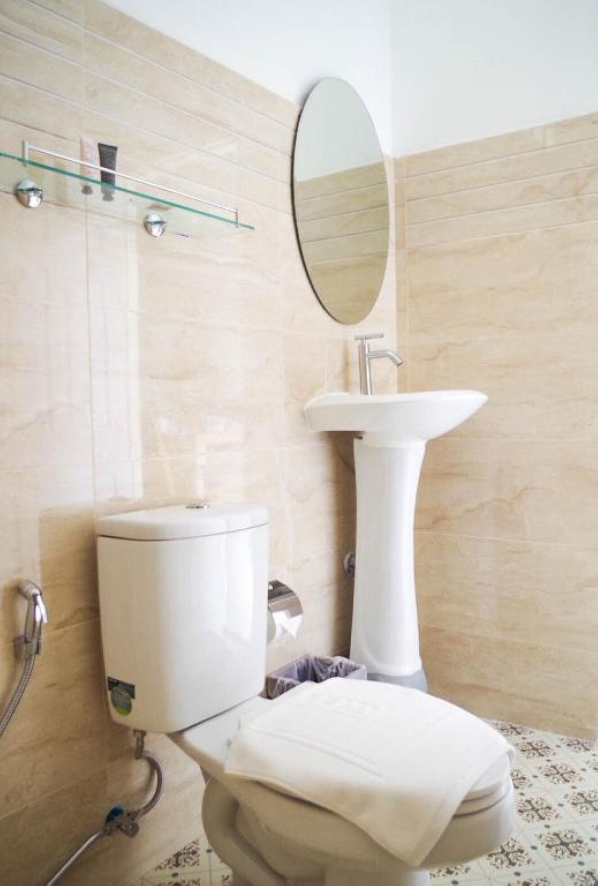 Une salle de bain équipée d’un WC, d’un lavabo, d’un miroir et d’une étagère en verre.
