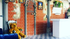 Een kamer met een blauwe bank, een teddybeer, een kamer met een patroon vloer, en een bakstenen muur met foto's en een decoratieve poort.